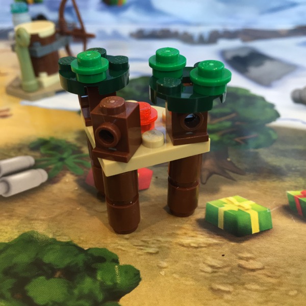 LEGO micro-build of the ewok village from 2015 with a light tan quarter circle connecting three dark brown trunks. The trees are shorter but have highlights of lighter green and there's a transparent orange stud to represent the central bonfire.