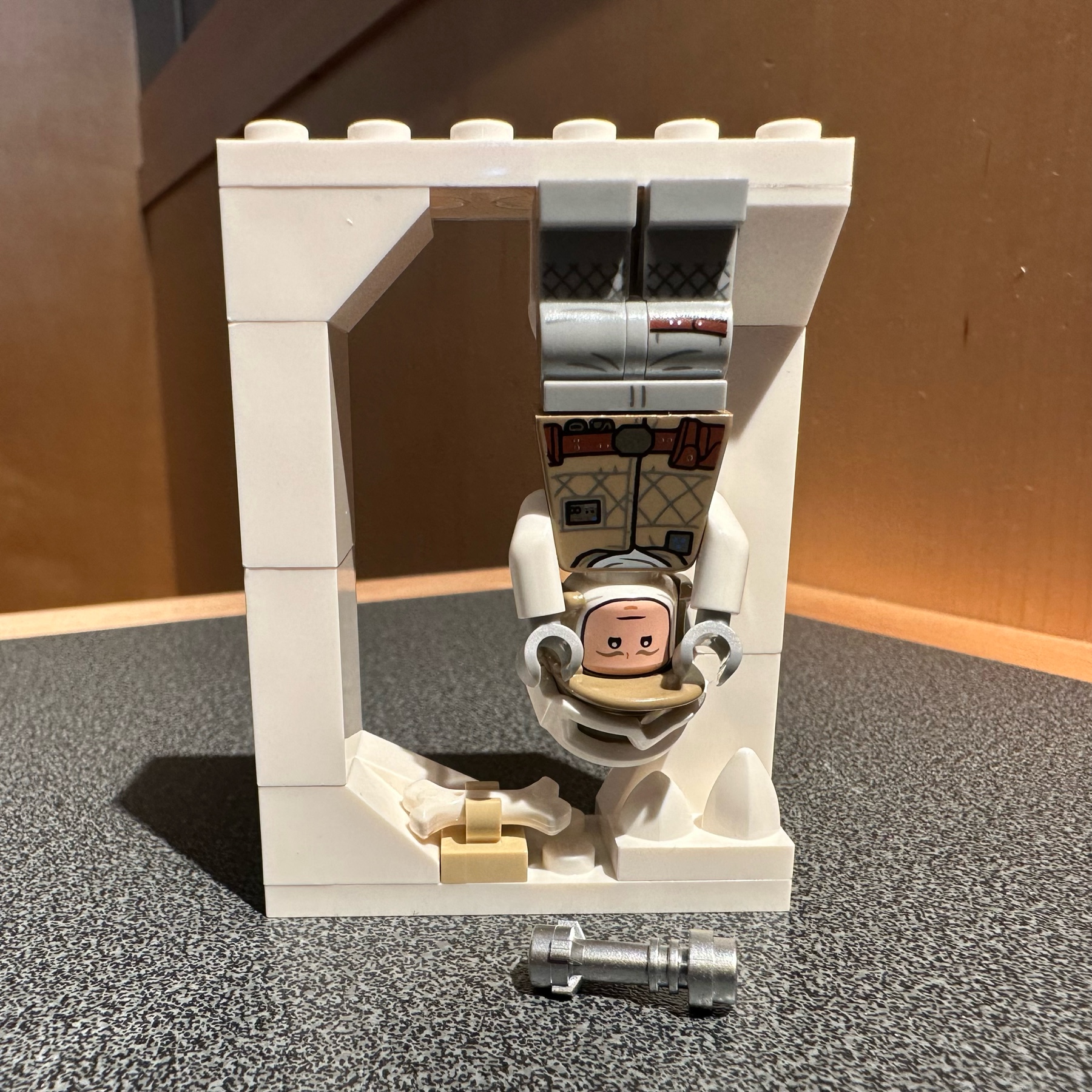 LEGO Luke Skywalker hangs upside down in the Wampa's ice cave with his light saber just out of reach