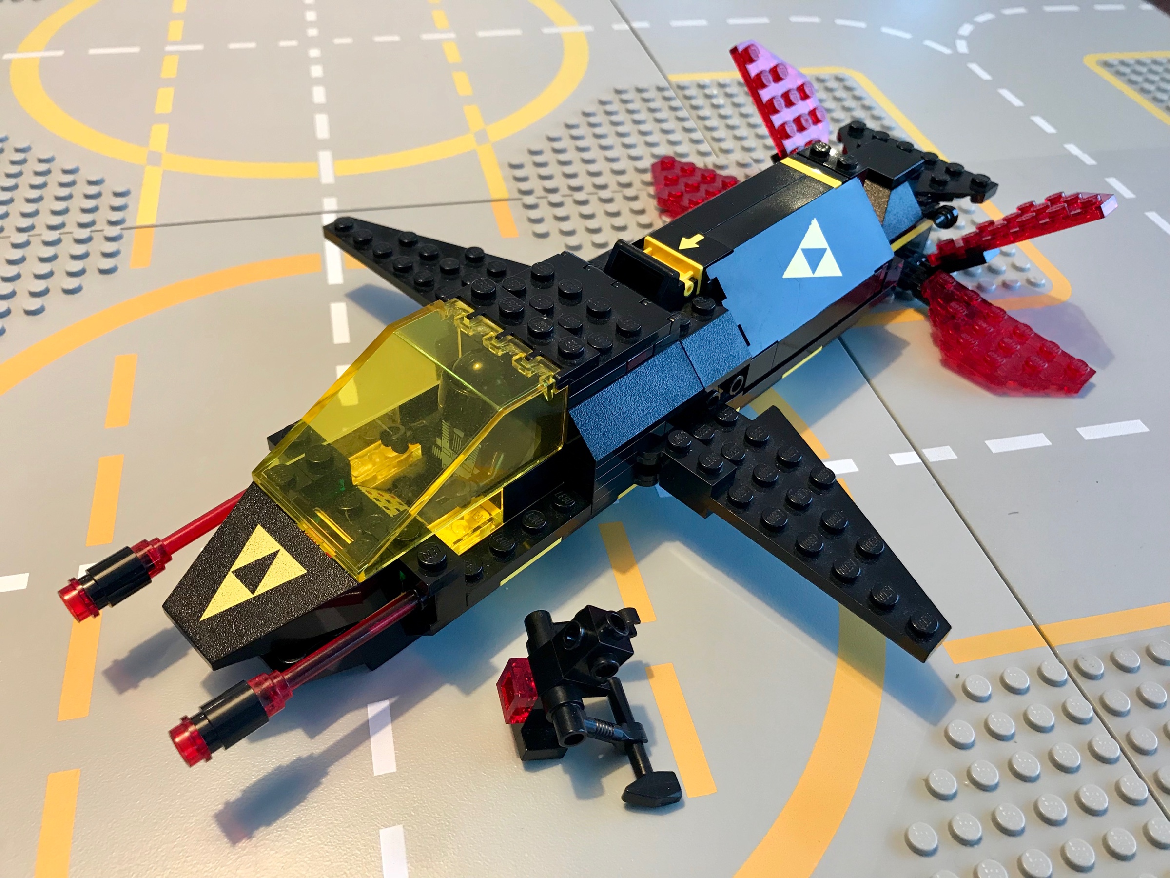 LEGO Blacktron spaceship in black with yellow highlights, transparent yellow windows, and four transparent red fins on the tail.