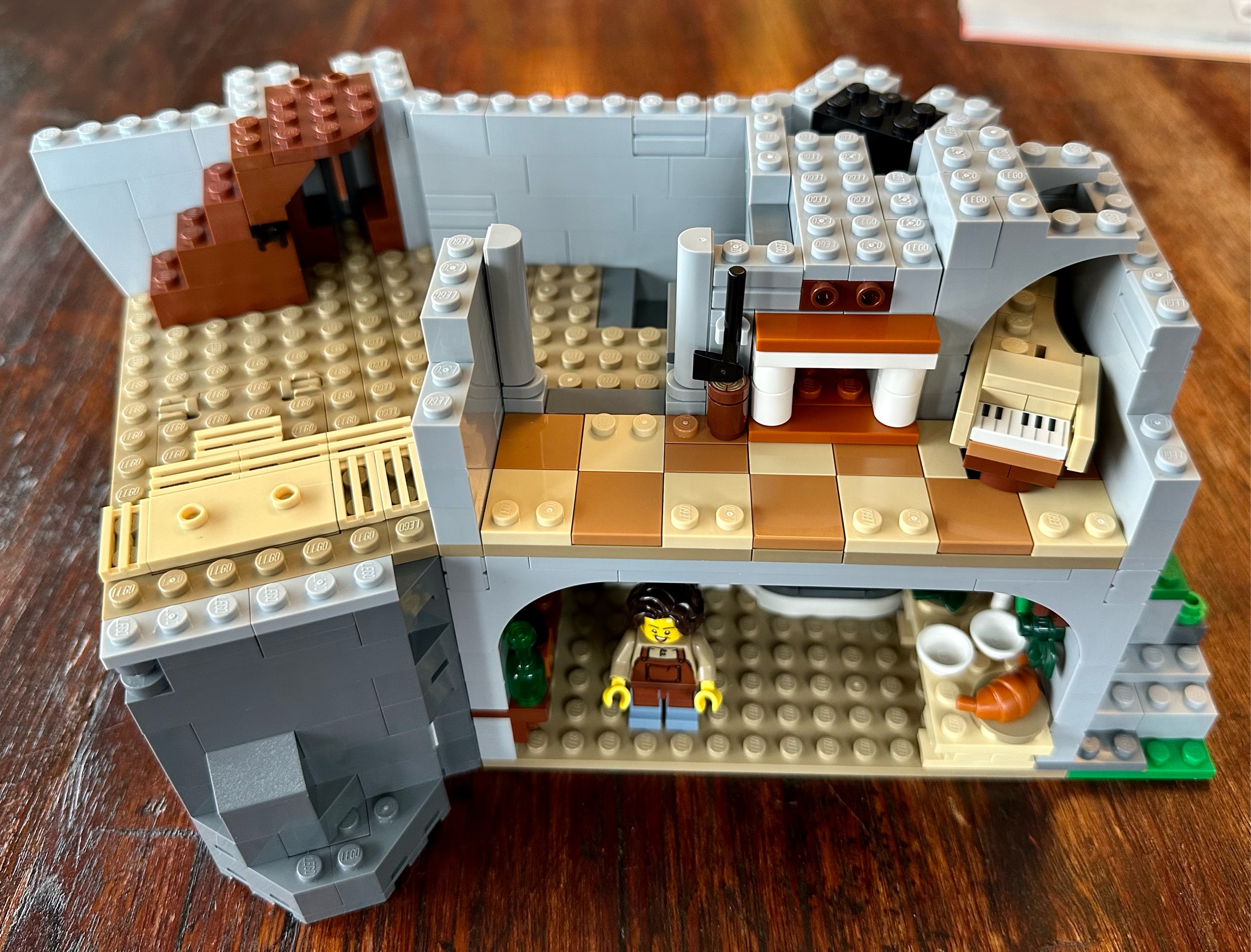 Section of a LEGO castle showing a partially constructed music room containing a harpsichord and a fireplace.