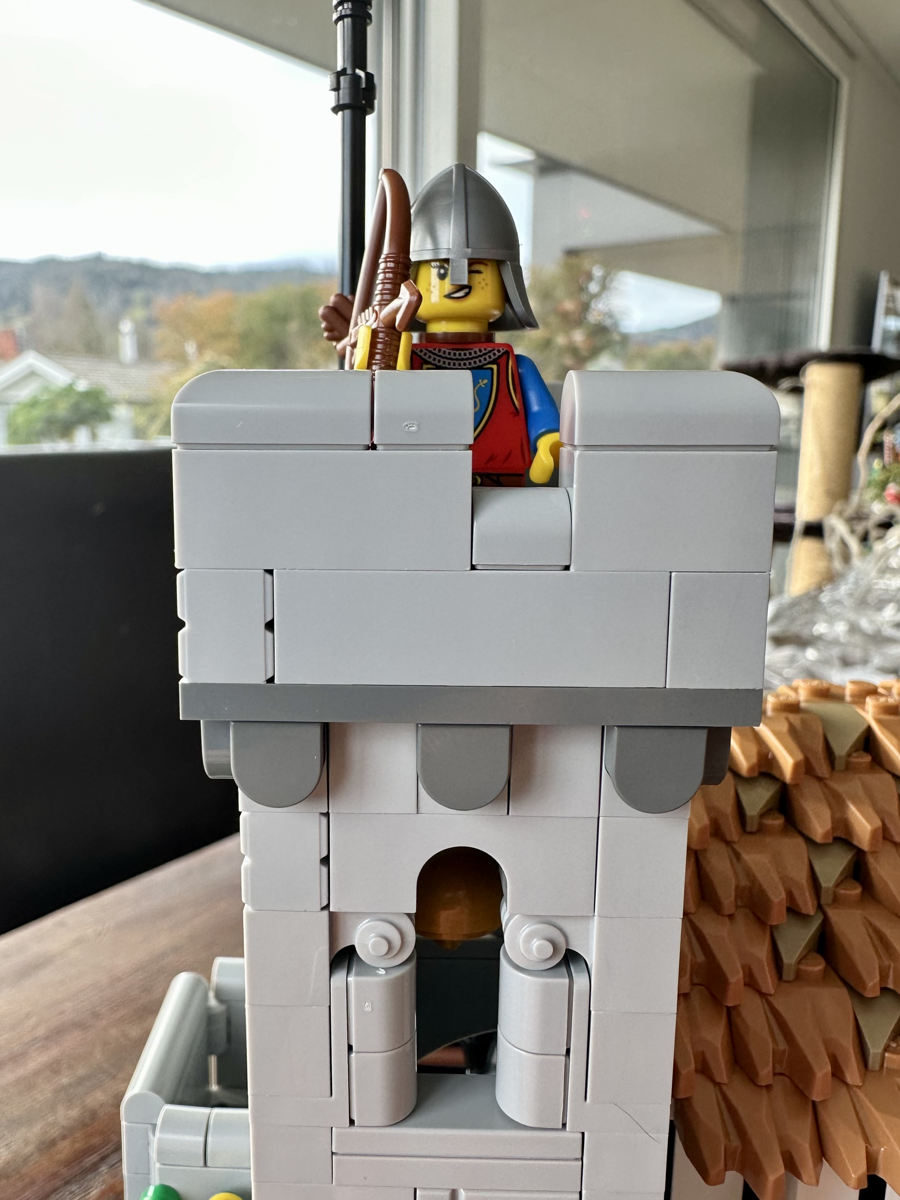 Close up of LEGO bell tower. The window has fancy scrollwork around it. An archer stands atop the tower.