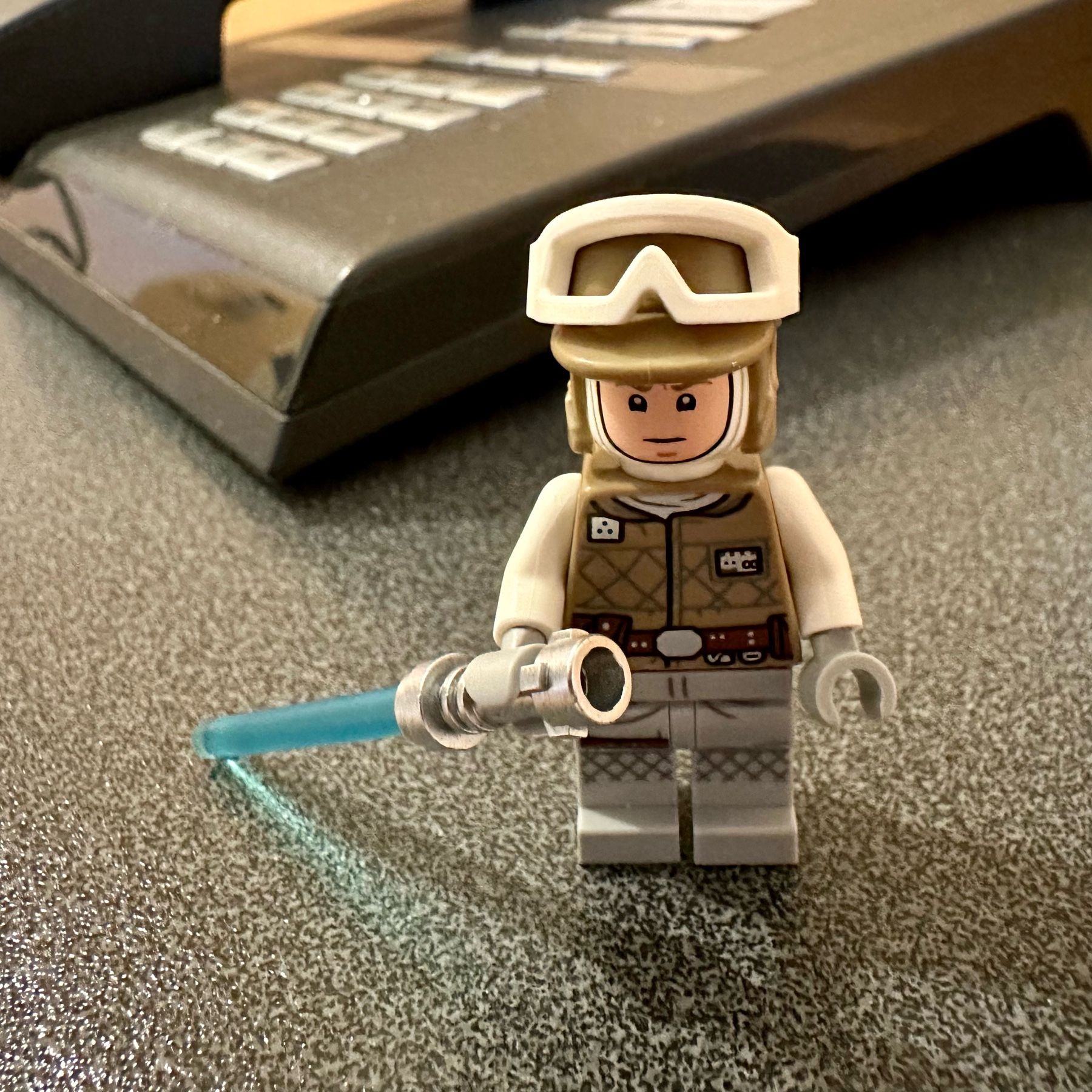 LEGO Luke Skywalker dressed in his Hoth cold weather outfit with a grim expression and wielding a blue lightsaber