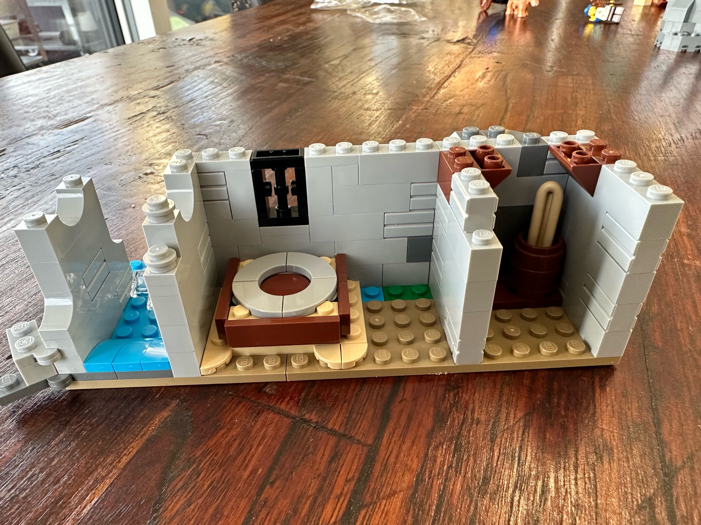 Interior view of LEGO castle section with a mill stone and a closet containing a barrel holding a baguette.