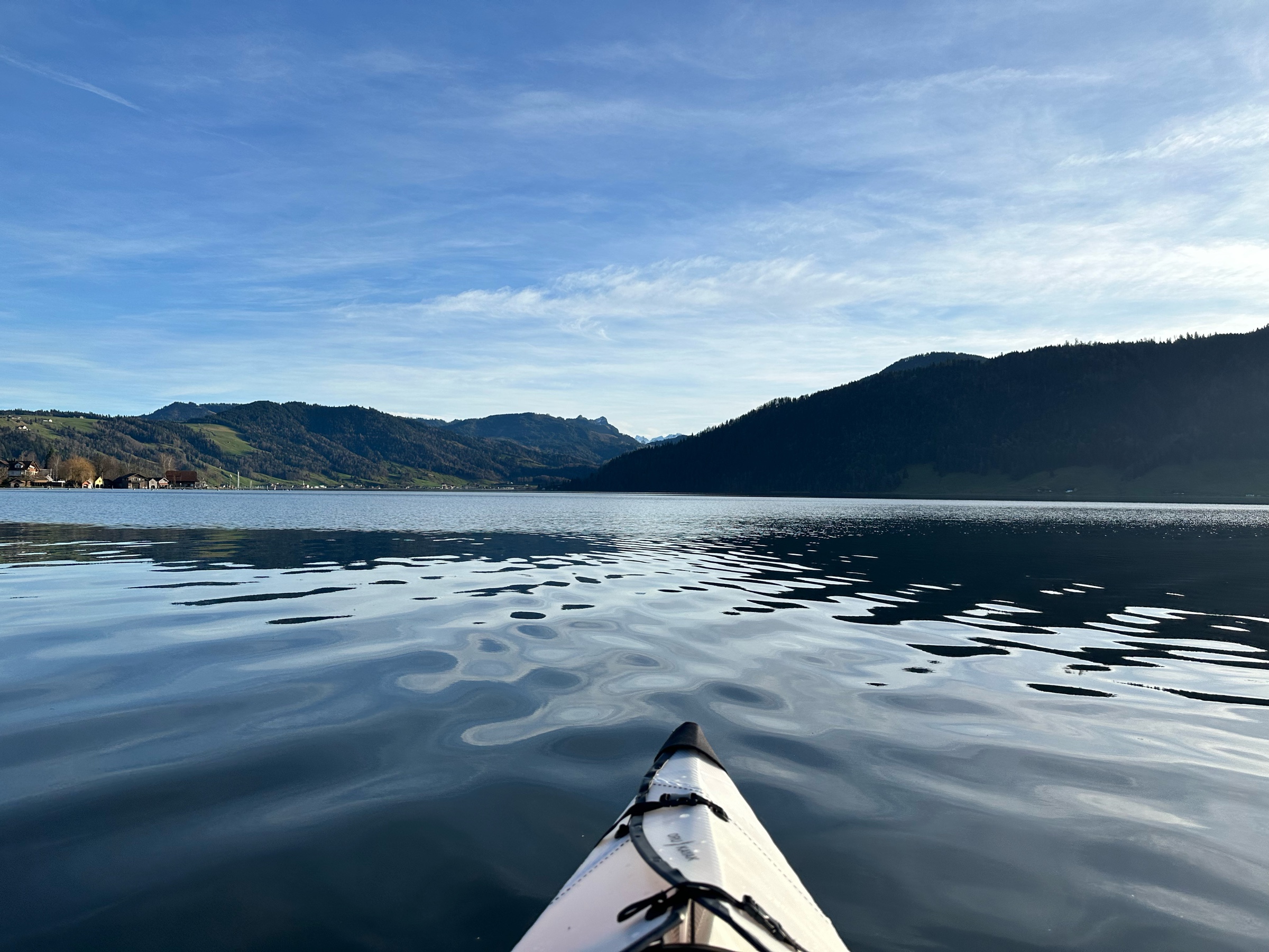 Lake with kayak tip in the foreground and hills and mountains in the background.