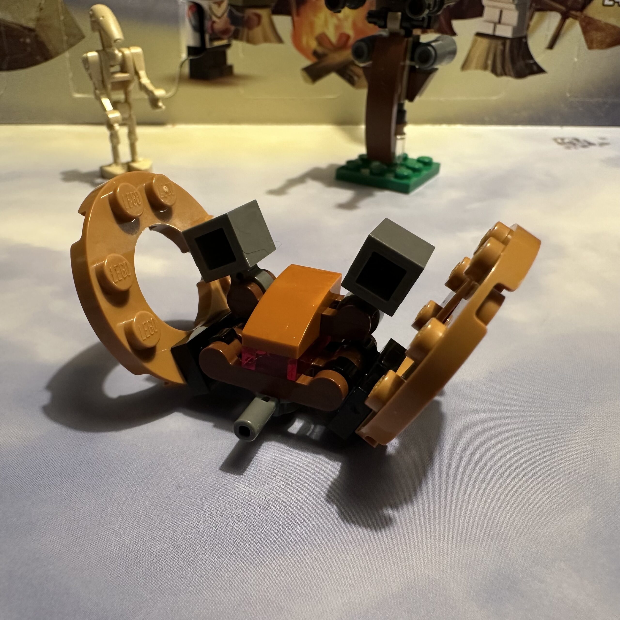 LEGO micro-build of a weird tank with two big brown wagon wheels mounted at an angle.