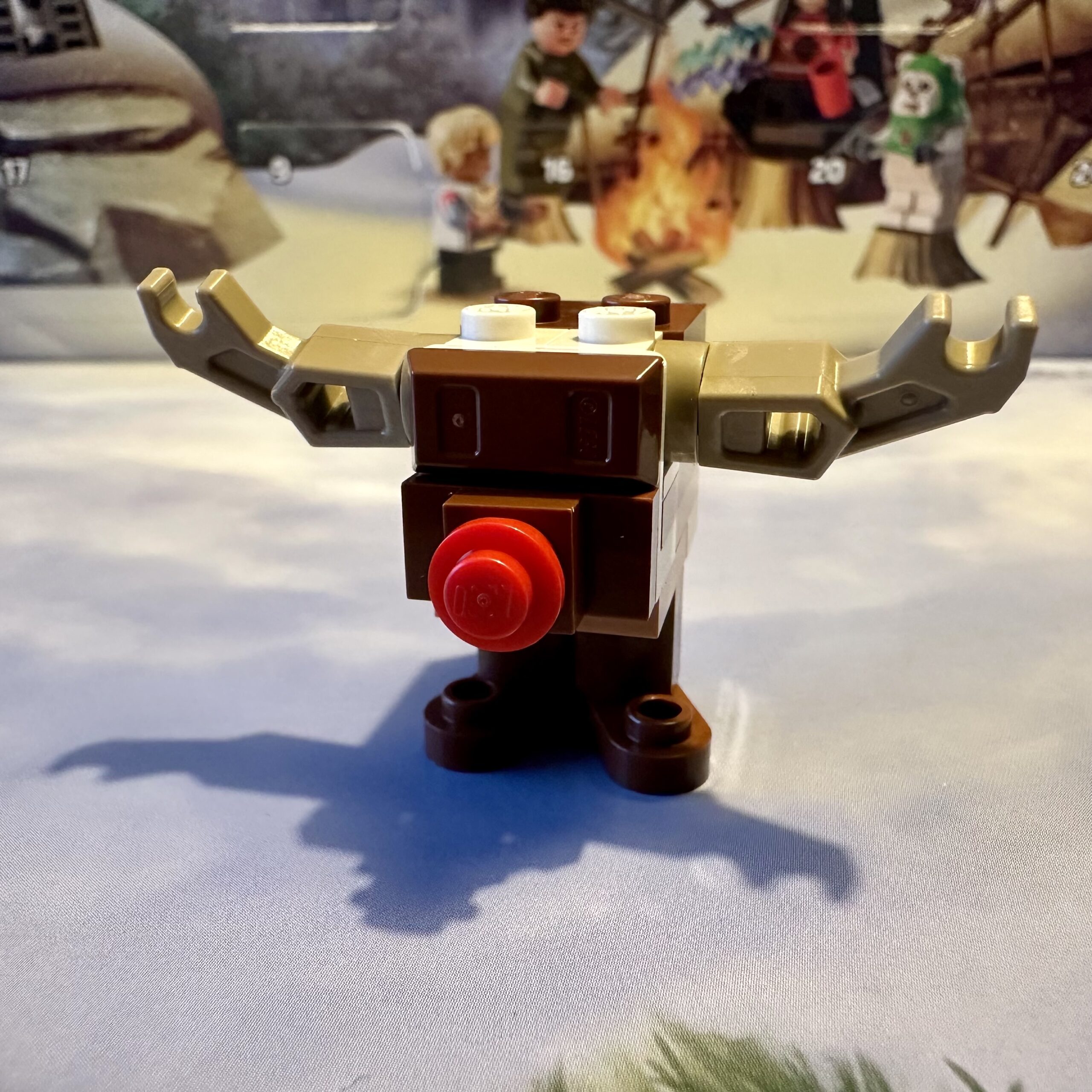 LEGO micro-build of a brown Star Wars GONK droid dressed as Rudolph with tan antlers and a red nose.