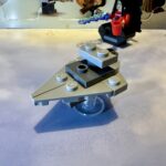 LEGO micro build of an Imperial Star Destroyer in light gray with dark gray highlights. It has the classic triangular wedge shape and raised bridge but is missing any engines.