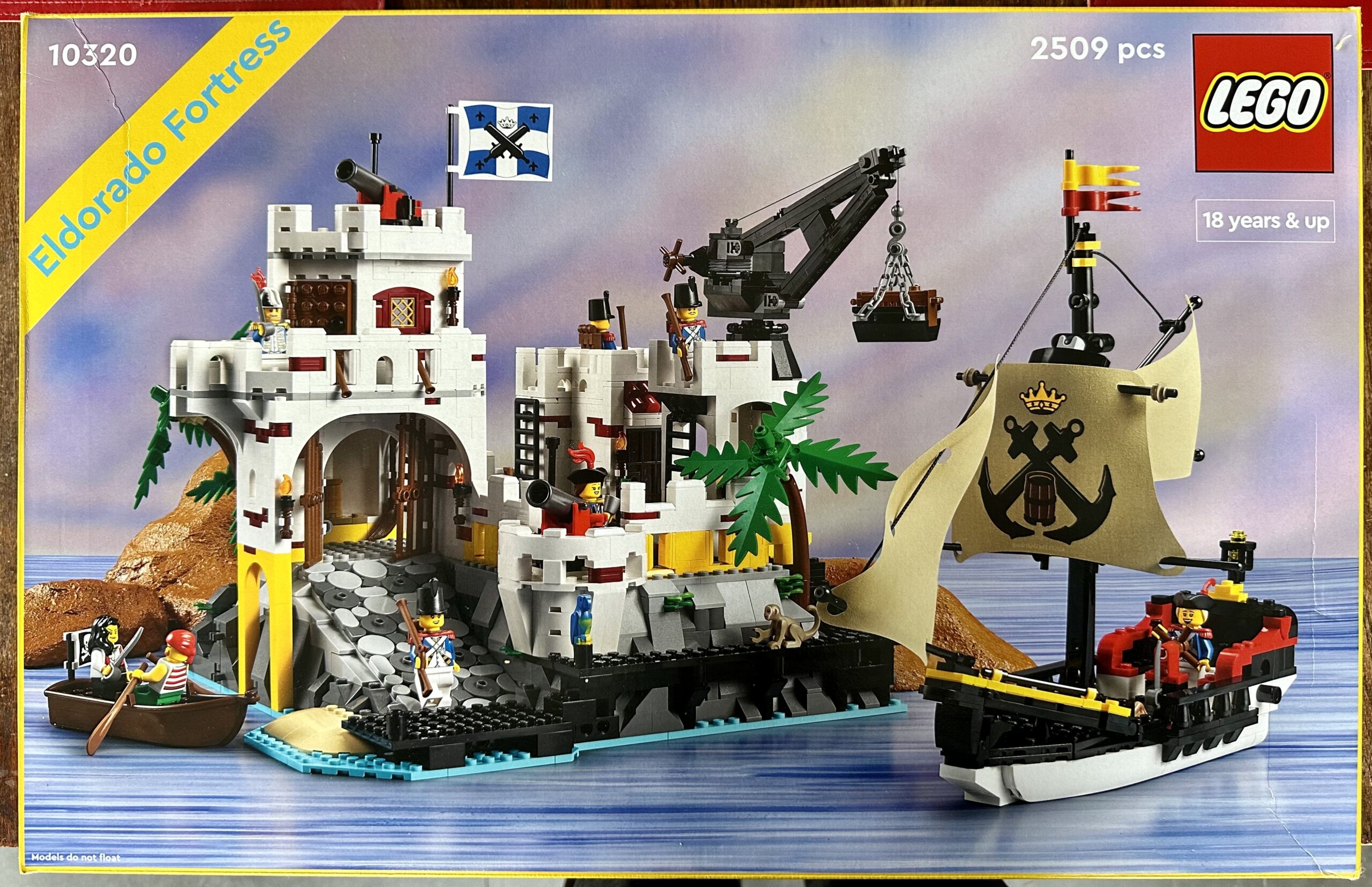 Box of LEGO set 10320 Eldorado Fortress from 2023. The box art shows an island fortress manned by soldiers, a small cutter, and a rowboat with a pair of pirates.