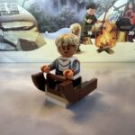 LEGO minifigure of Omega from the Bad Batch stands in a tiny sled because the minifigures with the short legs can't even sit.
