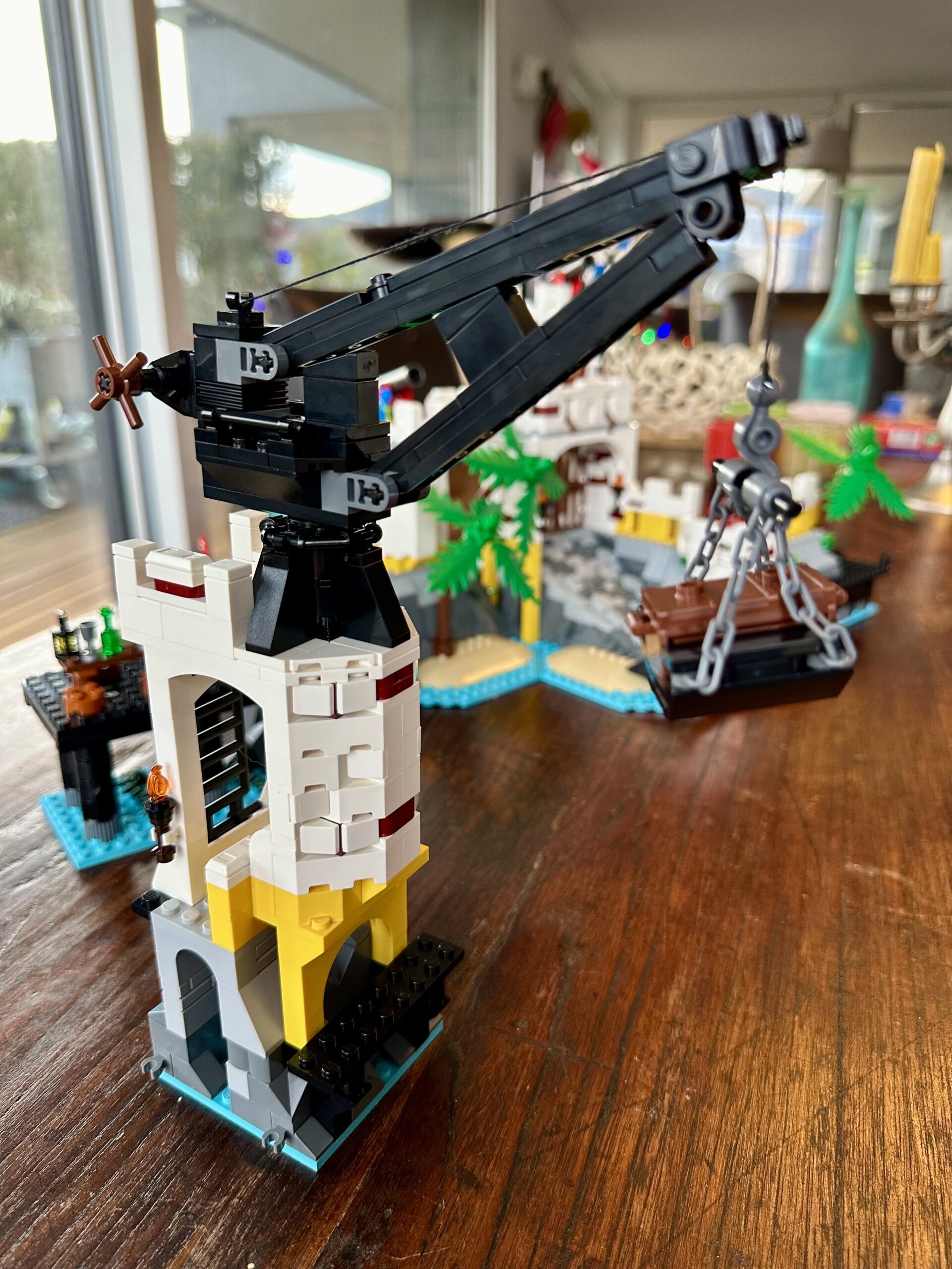 LEGO build of set 10320 Eldorado Fortress in progress. A small white and yellow tower with a black crane atop. The crane lifts a brown treasure chest.