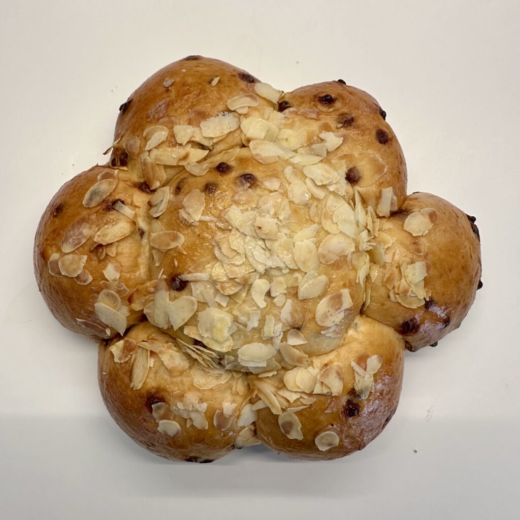 Dreikönigskuchen: a sweet bread with 6 lobes around a larger center. The bread has chocolate chips in it and is decorated with slivered almonds.