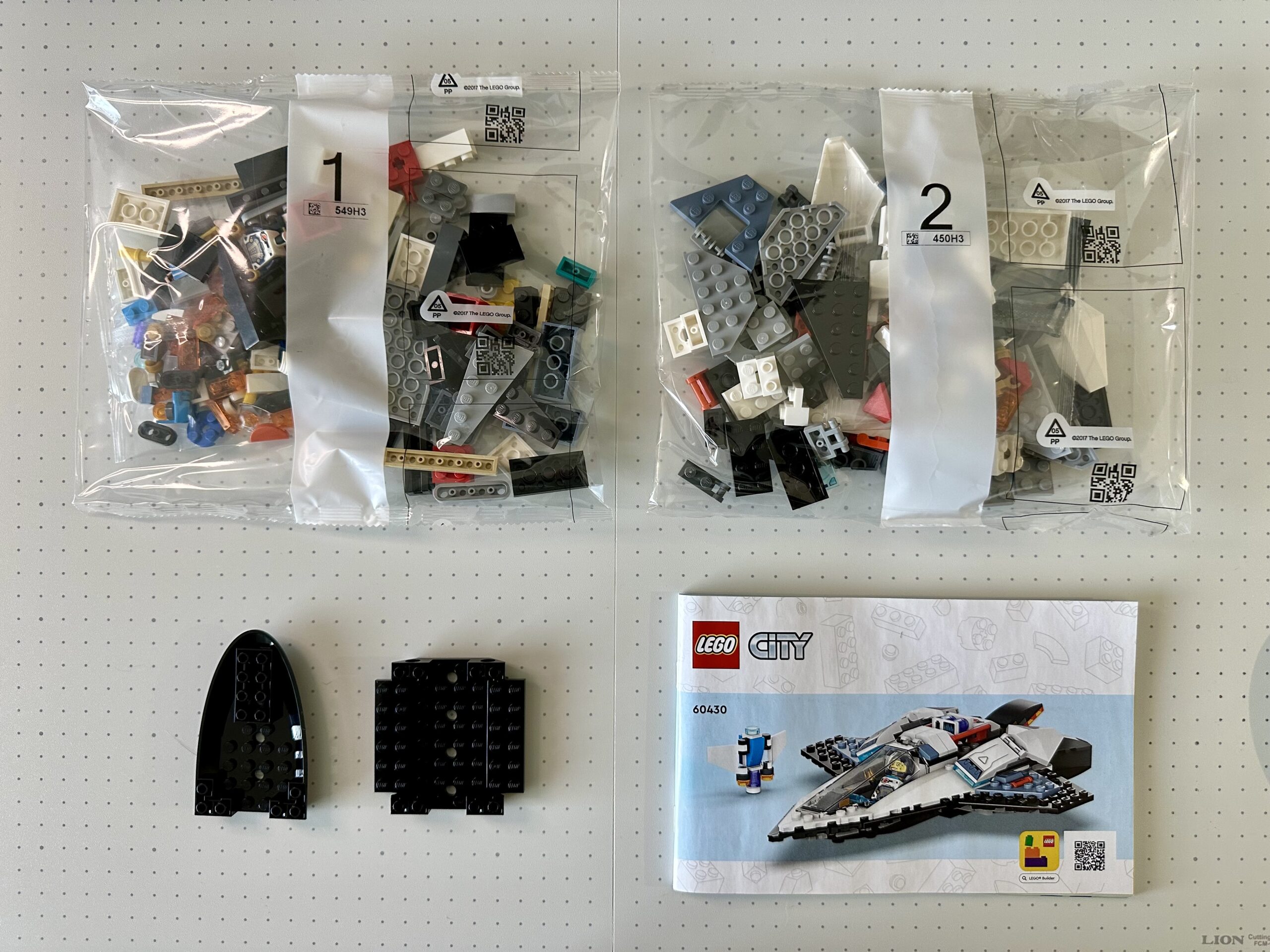 Two numbered bags of parts, instruction manual, and two larger loose pieces for LEGO set 60430.
