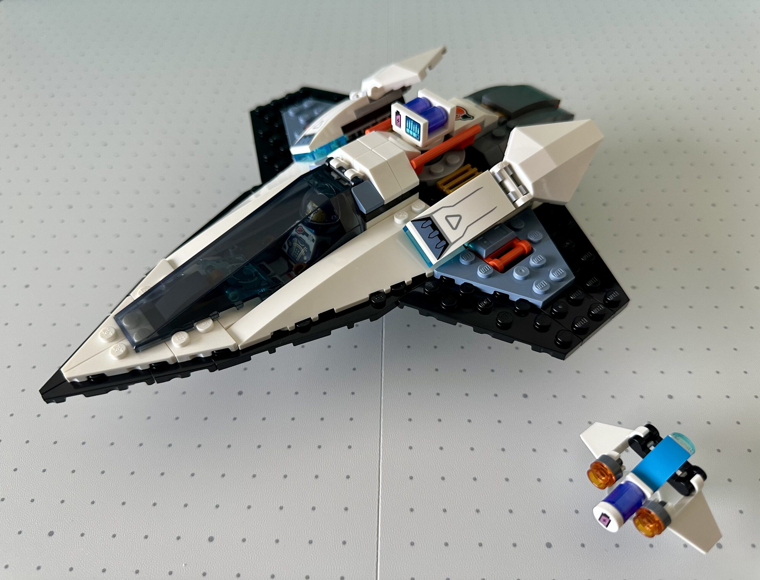 A speedy-looking black and white LEGO spaceship with a dark tinted canopy. A small drone flies nearby.