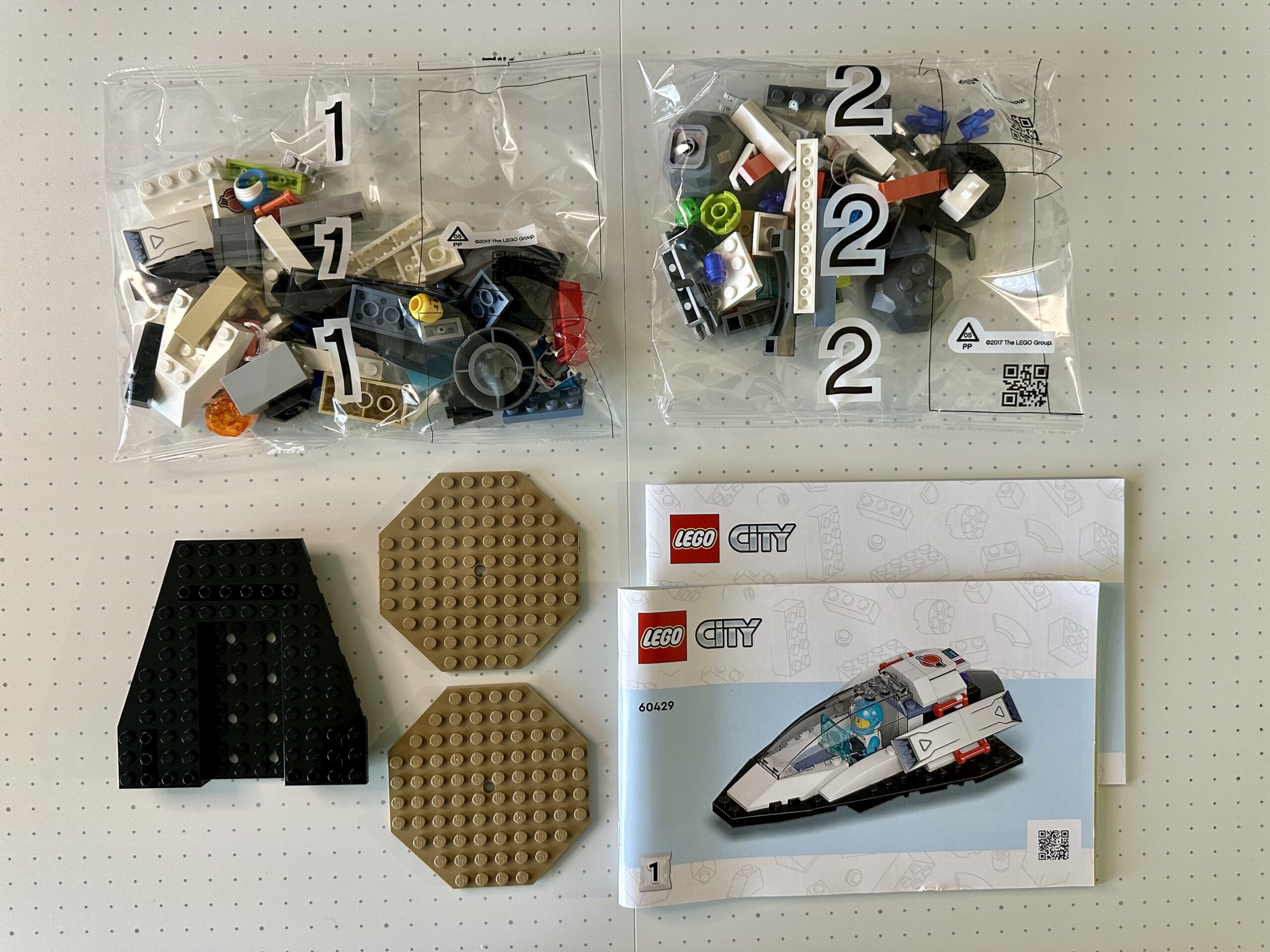 Two instruction manuals, two bags of parts, and three larger loose pieces for LEGO City Space set 60429.